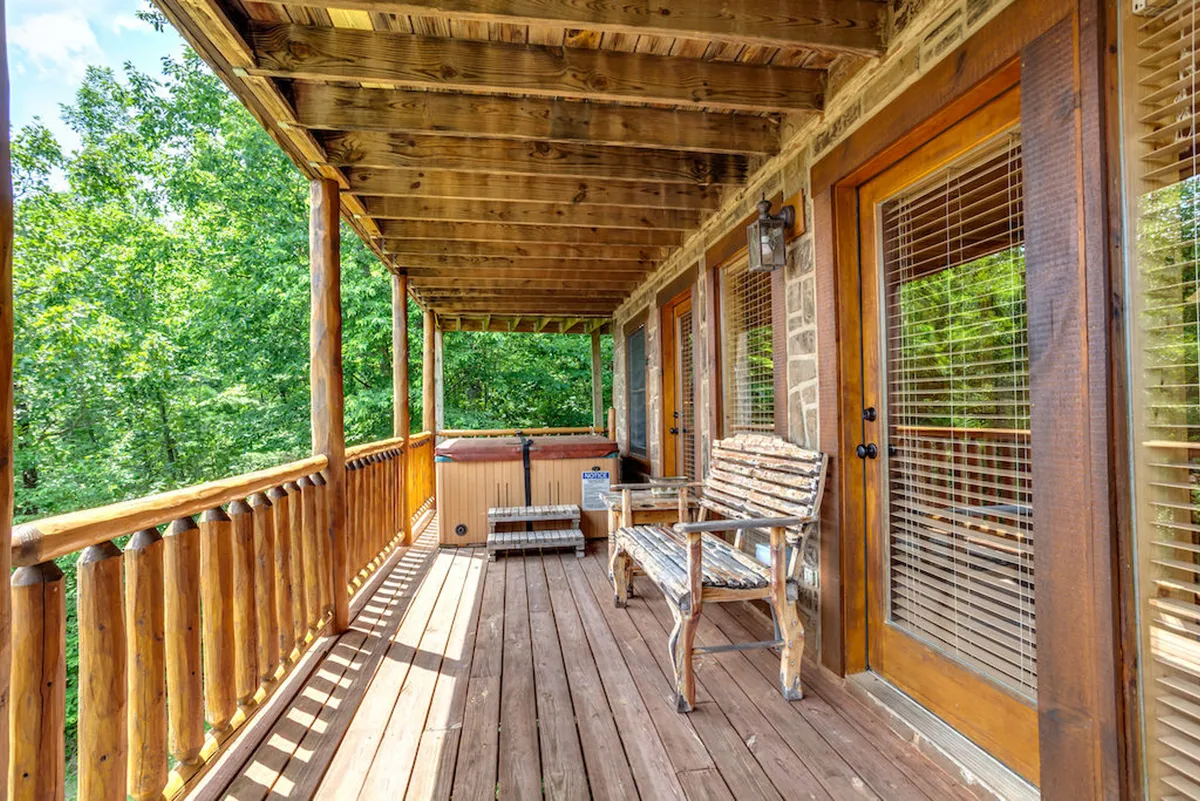 A wide wooden deck features a hot tub, rocking chair, and sturdy railing overlooking treetops. The space exudes peace and is ideal for enjoying mountain air, whether relaxing alone or socializing with friends and family.