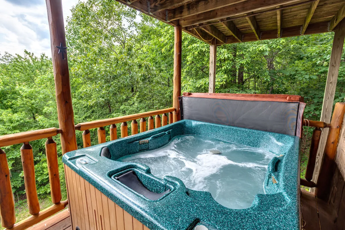 This image focuses on the private hot tub set against a backdrop of lush greenery, with a wooden railing enveloping the space. The atmosphere is tranquil, and the scene evokes relaxation and a strong connection to nature, inviting guests to enjoy starlit dips or a soothing soak any time of year.